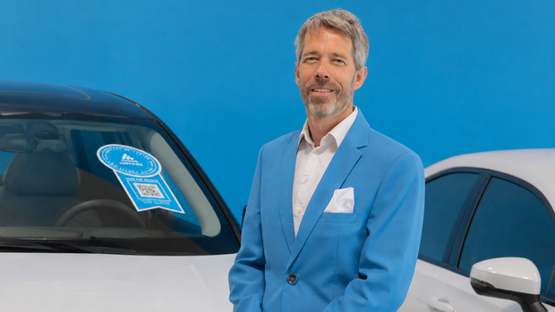 AVILOO-CEO Marcus Berger vor einem Elektroauto mit Hinweis auf den Batterietest