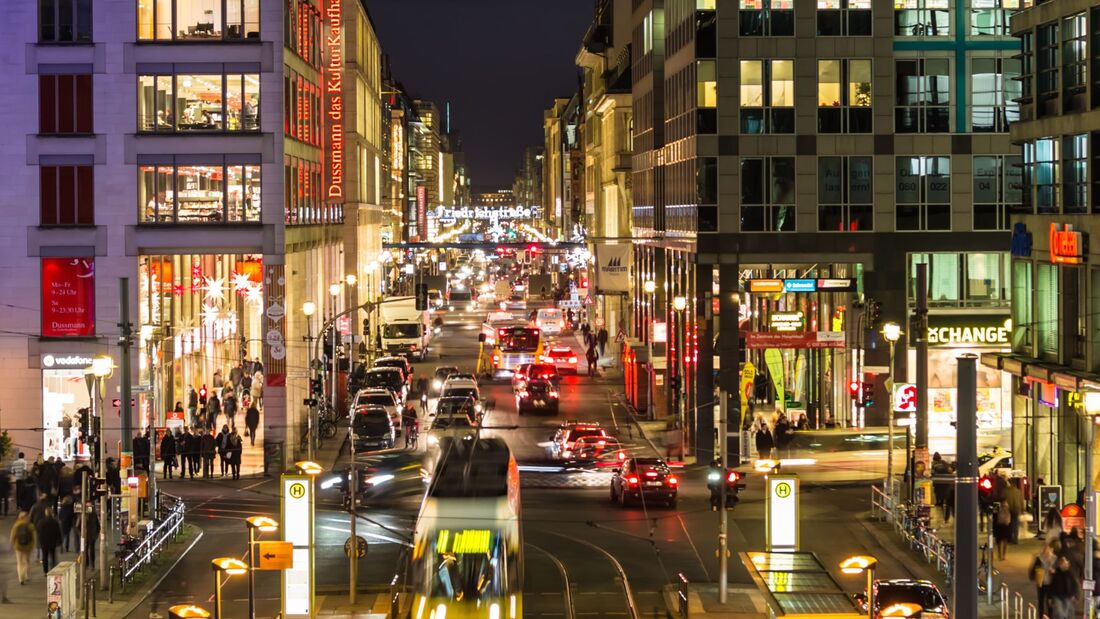 Abendlicher Verkehr auf der Friedrichstraße in Berlin: Autos, Bus und Straßenbahn stauen sich auf der belebten Einkaufsstraße.