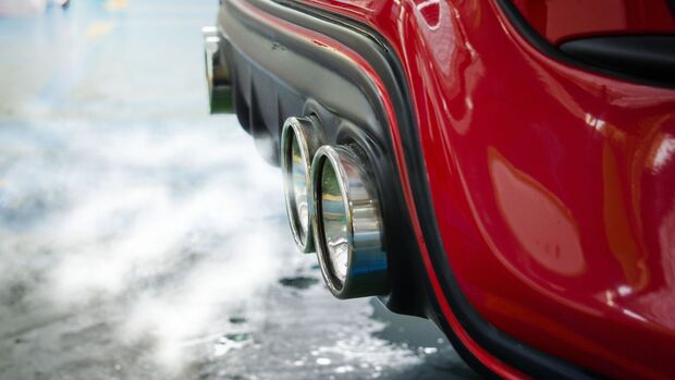 Abgasanlage eines Fahrzeugs mit sichtbaren Abgasen, Symbol für Emissionsregulierung.