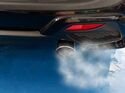 Abgase treten aus dem Auspuff eines Pkw aus und verdeutlichen die CO₂-Emissionen von Verbrennerfahrzeugen.
