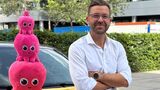 Achim Hirsch von Octopus Electric Vehicles vor einem gelben Elektroauto mit den pinken Octopus-Maskottchen.