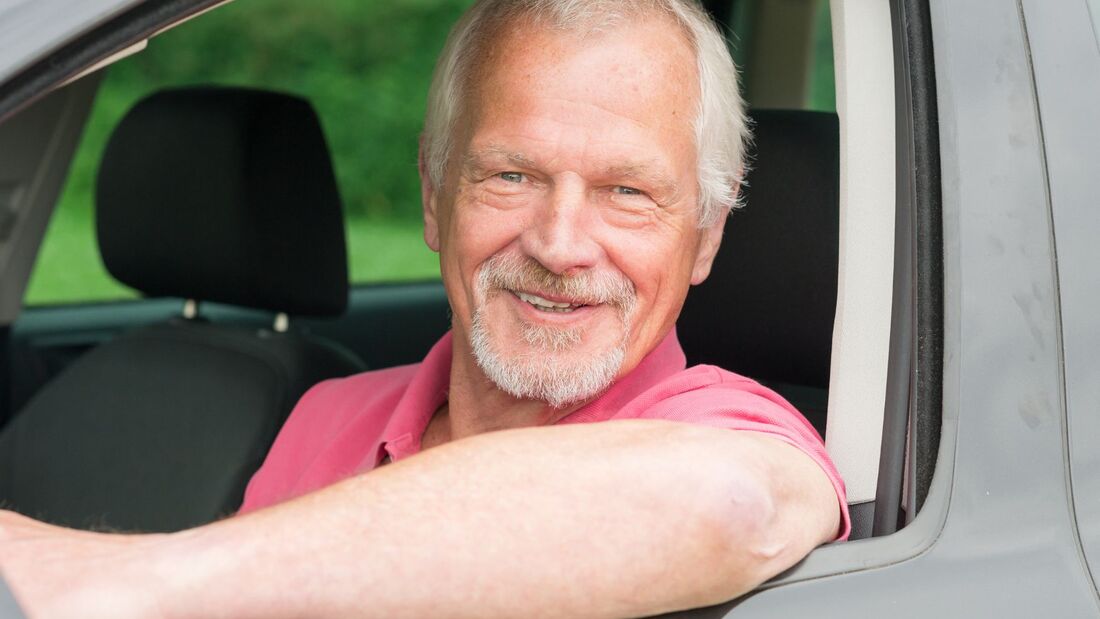 Älterer Mann mit grauem Bart lehnt lächelnd aus dem Autofenster – Symbolbild für Aktivrentner mit Dienstwagen