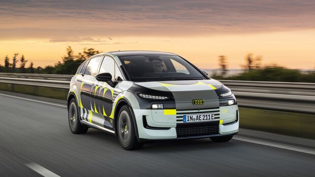 Audi A2 E-Tron Prototyp mit Tarnbeklebung fährt auf einer Autobahn aus Frontperspektive.