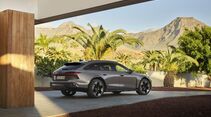 Audi A6 allroad in Dreiviertel-Heckansicht vor einer modernen Architektur mit Palmen und Bergkulisse.