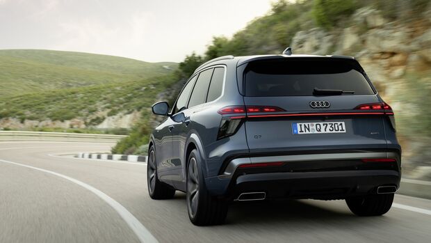 Audi Q7 Generation 3 in Heckansicht auf kurvenreicher Landstraße während der Fahrt.