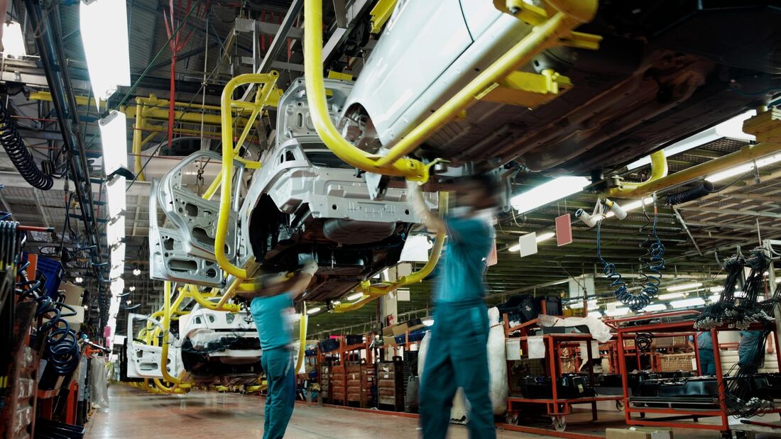 Automobilkarosserien in einer Fertigungshalle während der Montage, Mitarbeiter arbeiten an Fahrzeugrohkarossen in der industriellen Produktion.