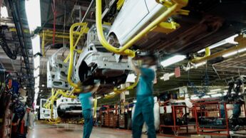 Automobilkarosserien in einer Fertigungshalle während der Montage, Mitarbeiter arbeiten an Fahrzeugrohkarossen in der industriellen Produktion.