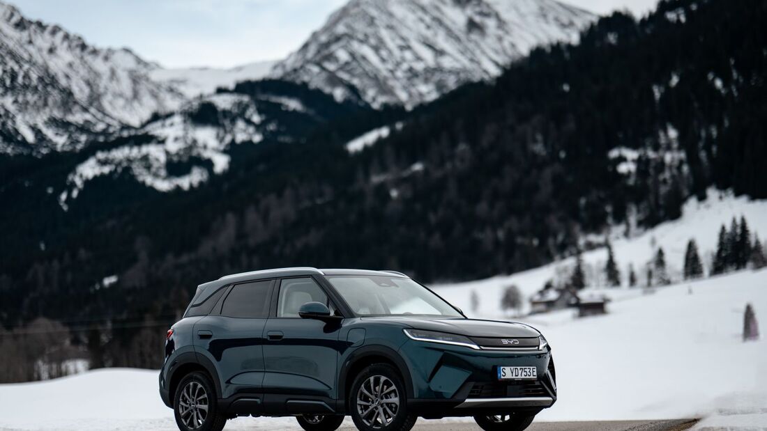 BYD Atto 2 DM-i in Front-Dreiviertelansicht auf verschneiter Straße mit Bergkulisse im Hintergrund.