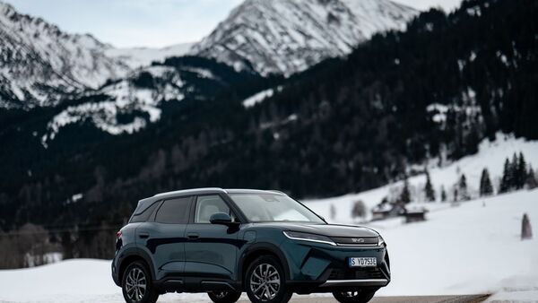 BYD Atto 2 DM-i in Front-Dreiviertelansicht auf verschneiter Straße mit Bergkulisse im Hintergrund.