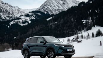 BYD Atto 2 DM-i in Front-Dreiviertelansicht auf verschneiter Straße mit Bergkulisse im Hintergrund.