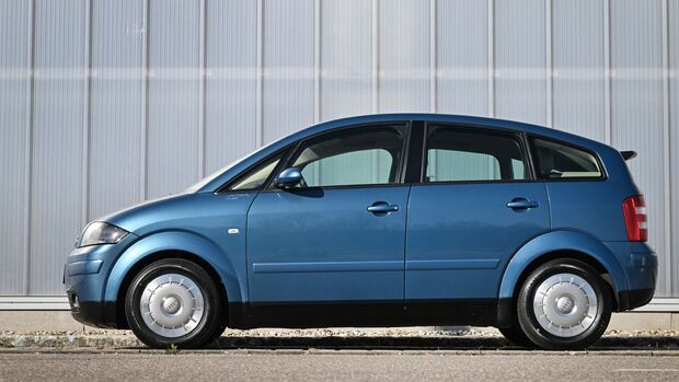 Blauer Audi A2 in vollständiger Seitenansicht vor einer hellen Industriehalle.