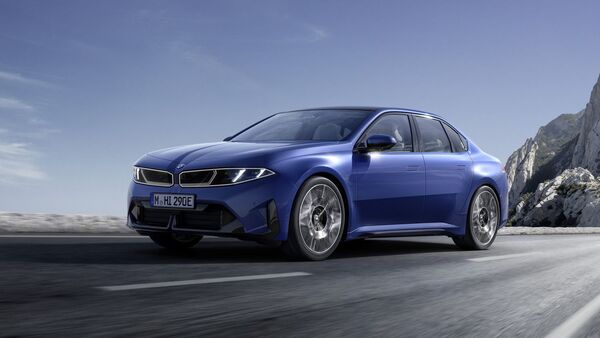 Blauer BMW i3 fährt auf einer Straße vor bergiger Landschaft