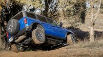 Blauer Ford Bronco bei Schrägfahrt im Gelände mit deutlich geneigter Karosserie auf Naturboden.