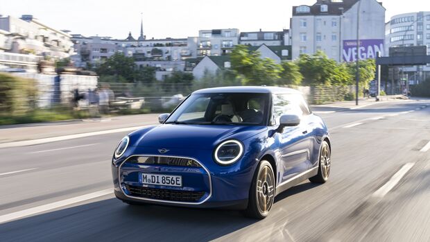 Blauer Mini Cooper SE fährt auf einer Stadtstraße bei Tageslicht