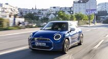 Blauer Mini Cooper SE fährt auf einer Stadtstraße bei Tageslicht