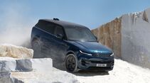 Blauer Range Rover Sport Electric fährt zwischen weißen Marmorblöcken durch einen Steinbruch.