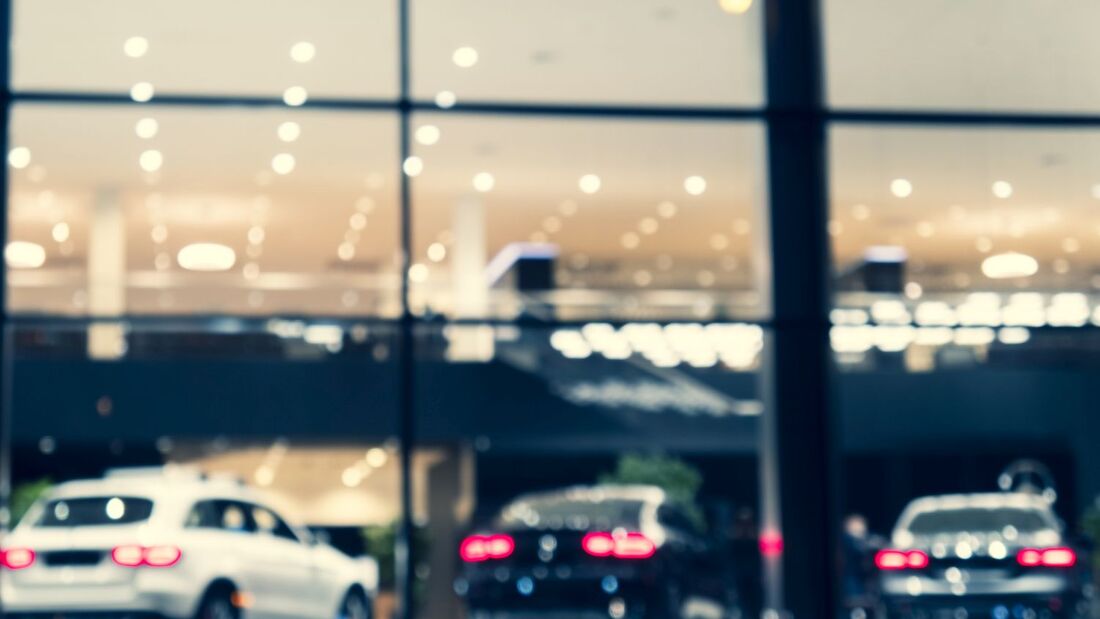 Blurred background with car dealership exterior. Abstract blurred photo of modern building motor showroom. Blur car show room office bokeh lights. Automobile retail shop
