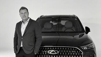 Chayne Brand, neuer Head of Brand Marketing & Communication bei Chery Auto Deutschland, vor einem schwarzen Chery-SUV