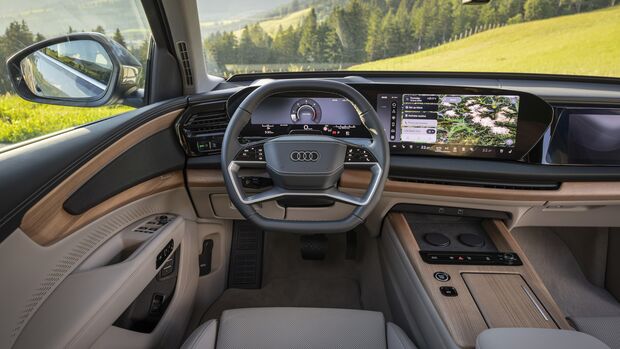 Cockpit des Audi Q7 mit digitalem Kombiinstrument, zentralem Touchscreen, Lenkrad, Holzdekor und heller Innenausstattung.