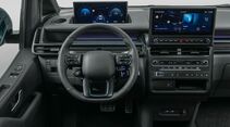 Cockpit des Hyundai Staria Elektro mit digitalem Kombiinstrument, zentralem Touchscreen und Multifunktionslenkrad.