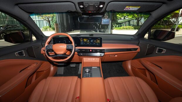 Cockpit des Kia K8 mit Digitaldisplay, Lenkrad und brauner Lederausstattung.