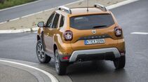 Dacia Duster der zweiten Generation in Heckansicht bei Geländefahrt mit Verschränkung auf unebenem Untergrund.