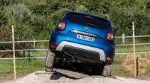 Dacia Duster der zweiten Generation in Heckansicht bei Geländefahrt mit Verschränkung auf unebenem Untergrund.