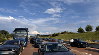Dichter Stau mit Pkw und Lkw auf einer Autobahn – unzuverlässige Fahrzeiten können Firmenflotten zusätzliche Zeit und Geld kosten.