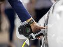 Dienstwagen-Fahrer steckt Ladestecker in ein Elektroauto an einer Ladestation.