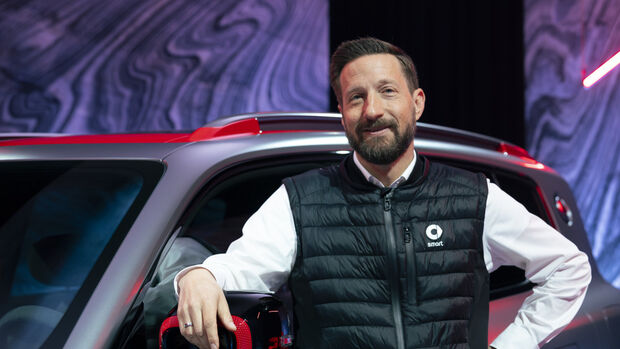Dirk Adelmann steht neben einem vollelektrischen smart SUV bei einer Markenpräsentation in Europa.