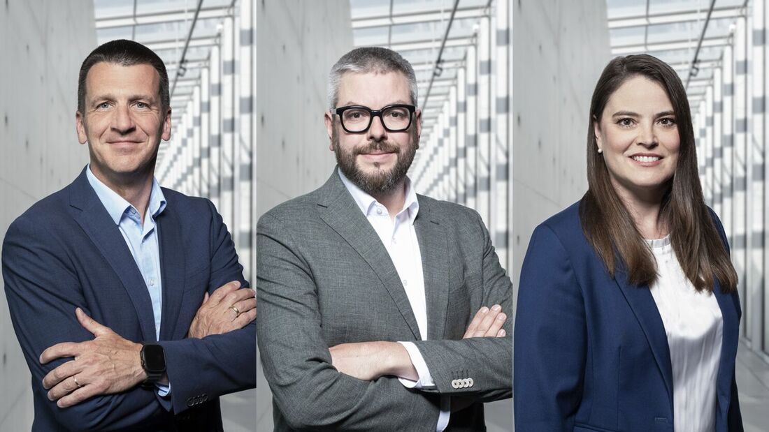 Drei Führungskräfte von Toyota Deutschland stehen in einem modernen Bürogebäude vor einer Glasfassade.