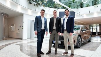 Drei Manager von Mazda Deutschland stehen in einem Showroom vor einem Fahrzeug. 