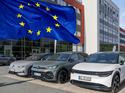 EU-Flagge vor geparkten Elektroautos an einem Unternehmensstandort.
