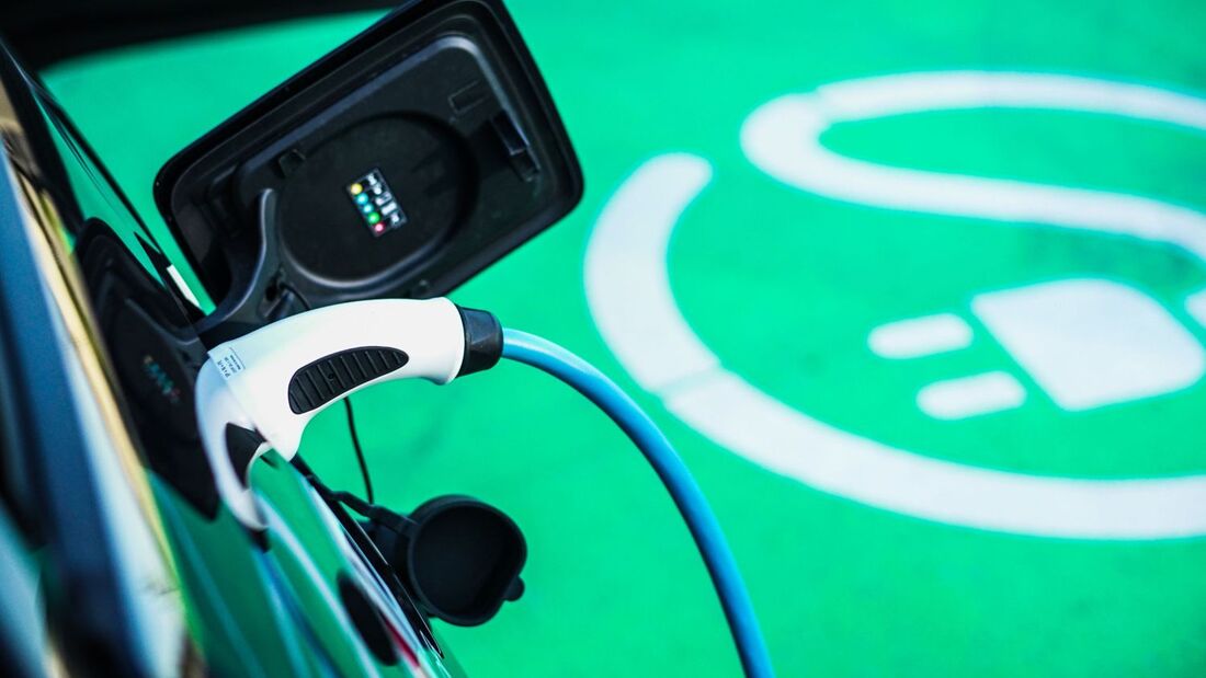 Ein Elektroauto lädt über ein angeschlossenes Ladekabel auf einer grün markierten Stellfläche für E-Fahrzeuge.