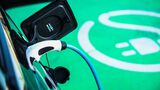 Ein Elektroauto lädt über ein angeschlossenes Ladekabel auf einer grün markierten Stellfläche für E-Fahrzeuge.
