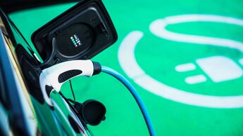 Ein Elektroauto lädt über ein angeschlossenes Ladekabel auf einer grün markierten Stellfläche für E-Fahrzeuge.
