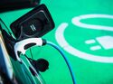 Ein Elektroauto lädt über ein angeschlossenes Ladekabel auf einer grün markierten Stellfläche für E-Fahrzeuge.
