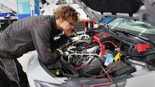 Ein Mitarbeiter von MHC Mobility führt Wartungsarbeiten im Motorraum eines Fahrzeugs durch.
