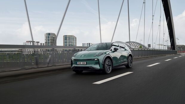 Ein Zeekr X fährt über eine Brücke in einer städtischen Umgebung, Frontansicht des kompakten E-SUV.