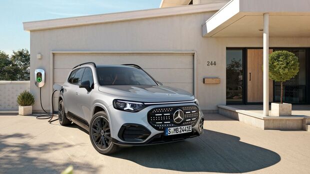 Ein elektrischer Mercedes-SUV lädt an einer Wallbox vor einem Wohnhaus.