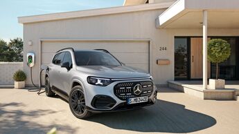 Ein elektrischer Mercedes-SUV lädt an einer Wallbox vor einem Wohnhaus.