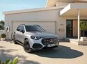 Ein elektrischer Mercedes-SUV lädt an einer Wallbox vor einem Wohnhaus.