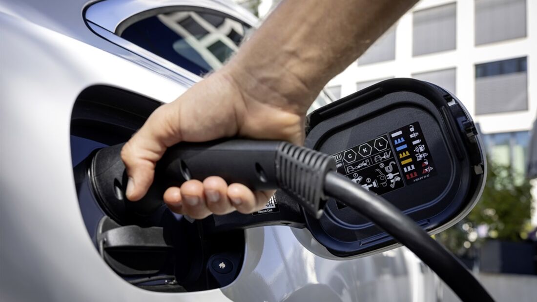Eine Hand verbindet ein Ladekabel mit der Ladebuchse eines Elektroautos.