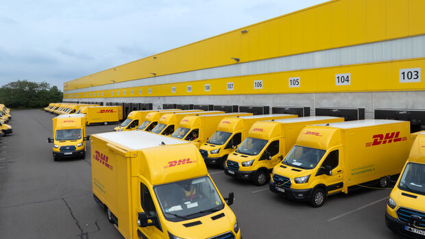 Elektrische Ford Transporter der DHL stehen an einem Logistikzentrum im Flotteneinsatz.