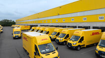 Elektrische Ford Transporter der DHL stehen an einem Logistikzentrum im Flotteneinsatz.