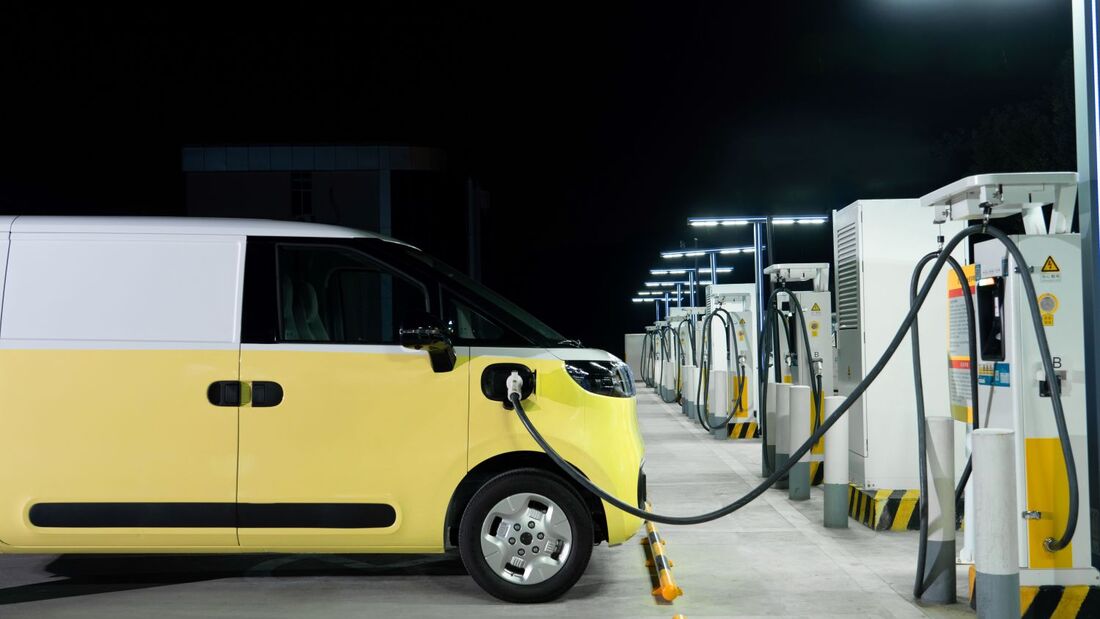 Elektrischer Transporter lädt nachts an einer Schnellladestation mit mehreren Ladepunkten.