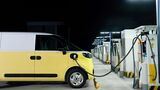 Elektrischer Transporter lädt nachts an einer Schnellladestation mit mehreren Ladepunkten.