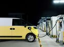 Elektrischer Transporter lädt nachts an einer Schnellladestation mit mehreren Ladepunkten.