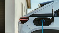 Elektro-Dienstwagen wird an einer privaten Wallbox am Wohnhaus geladen, Ladekabel ist mit dem Fahrzeug verbunden.