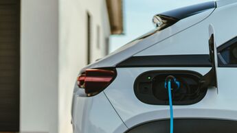 Elektro-Dienstwagen wird an einer privaten Wallbox am Wohnhaus geladen, Ladekabel ist mit dem Fahrzeug verbunden.